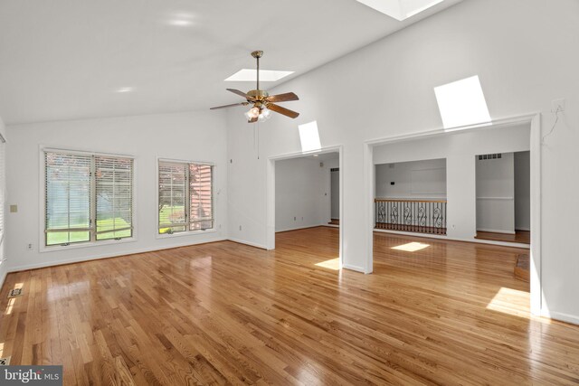 unfurnished living room featuring light wood-type flooring, ceiling fan, a skylight, and high vaulted ceiling