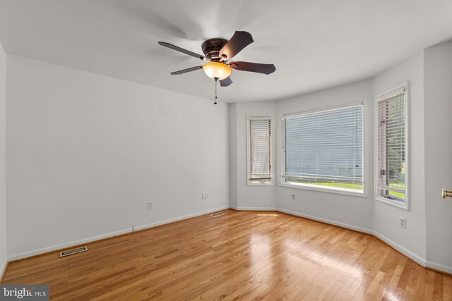 spare room with ceiling fan, baseboards, plenty of natural light, and wood finished floors