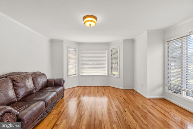 living area with baseboards, visible vents, ornamental molding, and light wood-type flooring