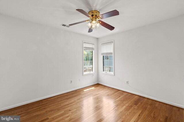unfurnished room with baseboards, ceiling fan, wood finished floors, and visible vents