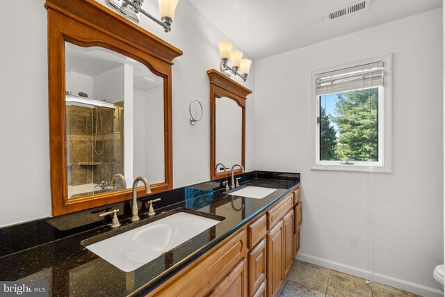 full bath with double vanity, a shower with door, visible vents, and a sink