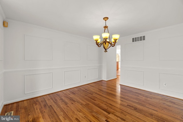 unfurnished dining area with ornamental molding, a decorative wall, and a chandelier