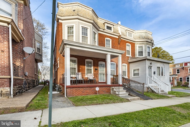 multi unit property featuring mansard roof, covered porch, and brick siding