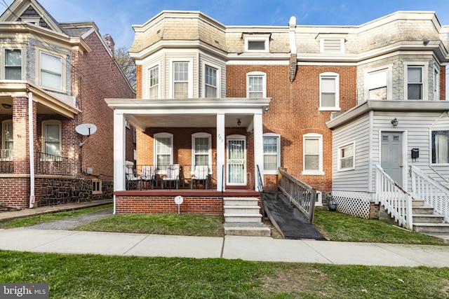 view of property with covered porch, entry steps, and brick siding