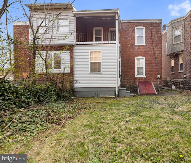back of property featuring brick siding, fence, and a yard