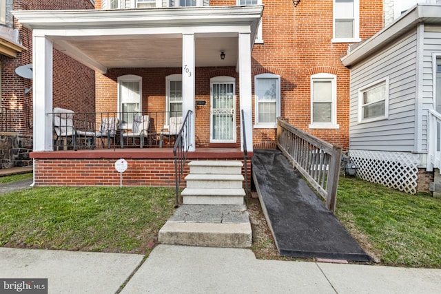 doorway to property featuring covered porch and brick siding