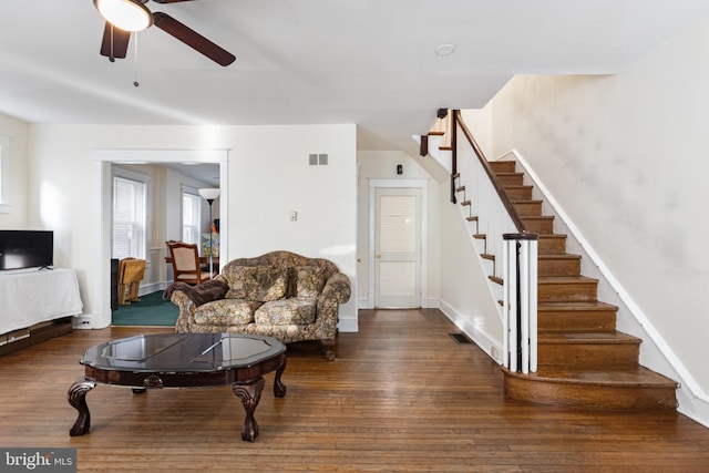 living area with stairway, hardwood / wood-style flooring, baseboards, visible vents, and a ceiling fan