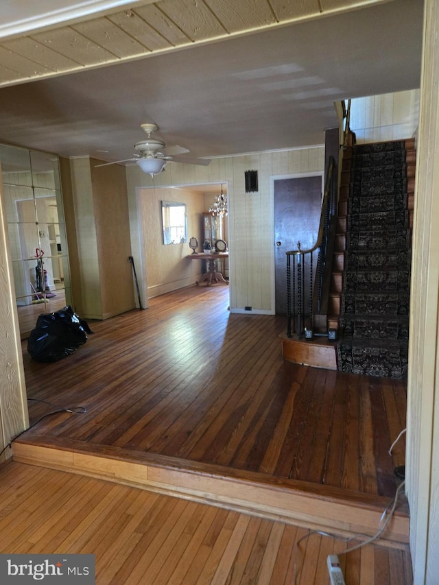 unfurnished living room with ceiling fan, hardwood / wood-style flooring, and stairs