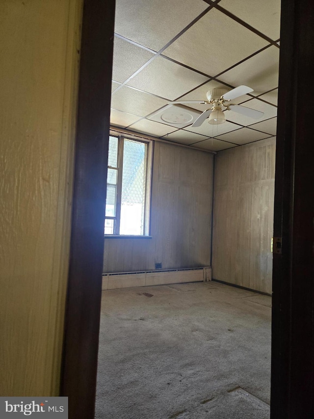 carpeted spare room with a paneled ceiling and baseboard heating