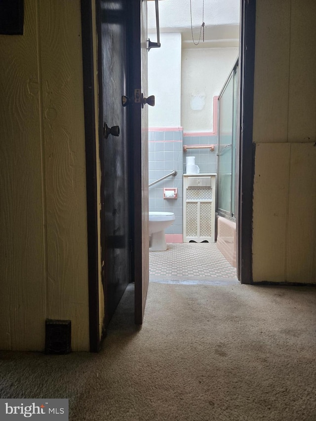 hall with carpet and tile walls