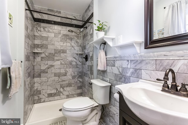 bathroom with vanity, tile walls, toilet, and tiled shower