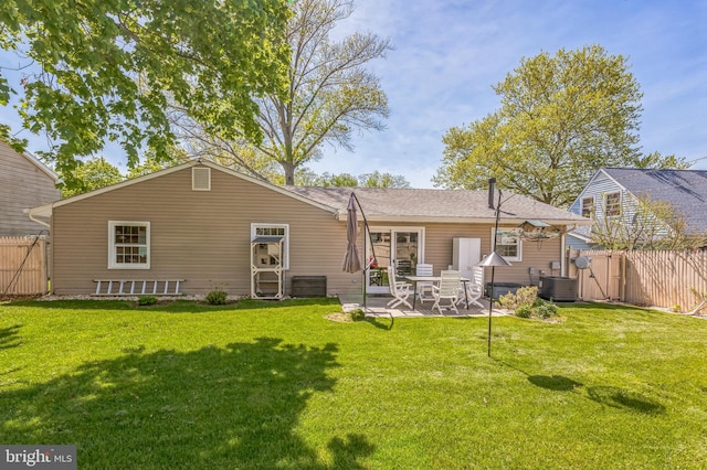 rear view of house with fence and a lawn