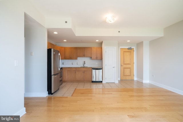 kitchen with appliances with stainless steel finishes, light countertops, light wood-style flooring, and baseboards