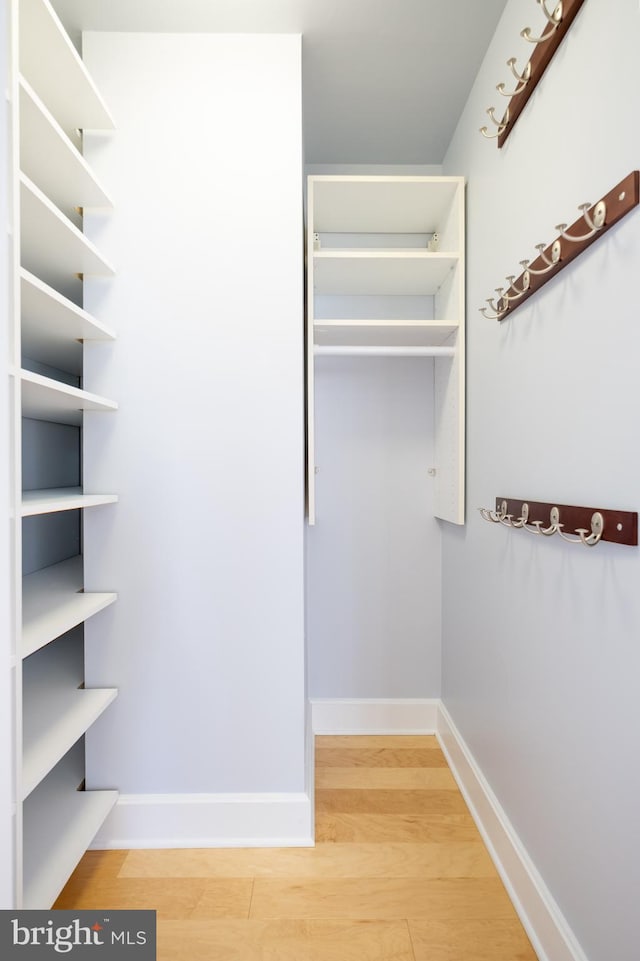 walk in closet with wood finished floors