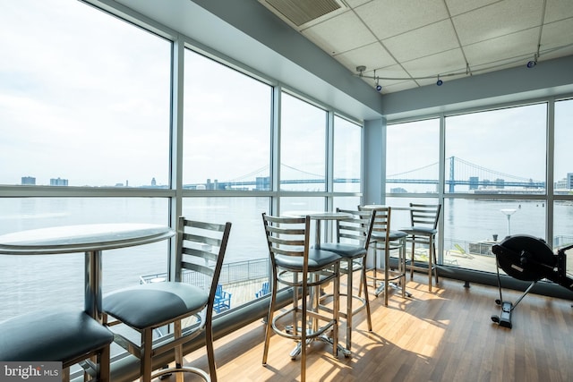 sunroom featuring visible vents, a water view, and a healthy amount of sunlight