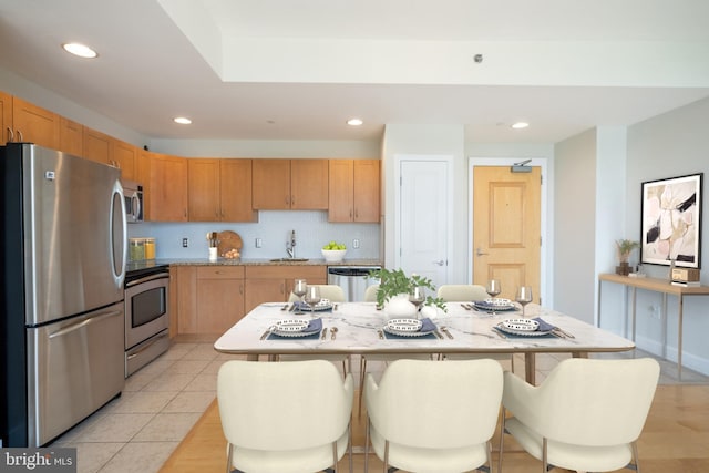 kitchen featuring recessed lighting, a breakfast bar, stainless steel appliances, light countertops, and a sink