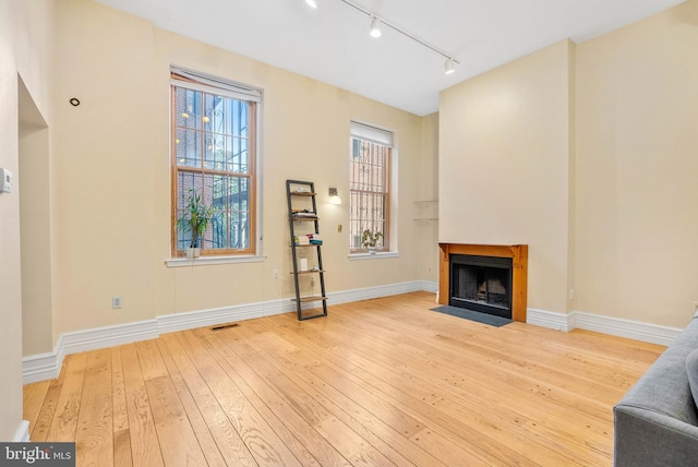 914 Spruce St Unit 9, Philadelphia, PA 19107 - unfurnished living room featuring a fireplace with flush hearth, wood-type flooring, track lighting, visible vents, and baseboards