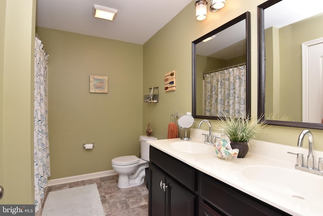full bath with a sink, baseboards, toilet, and double vanity