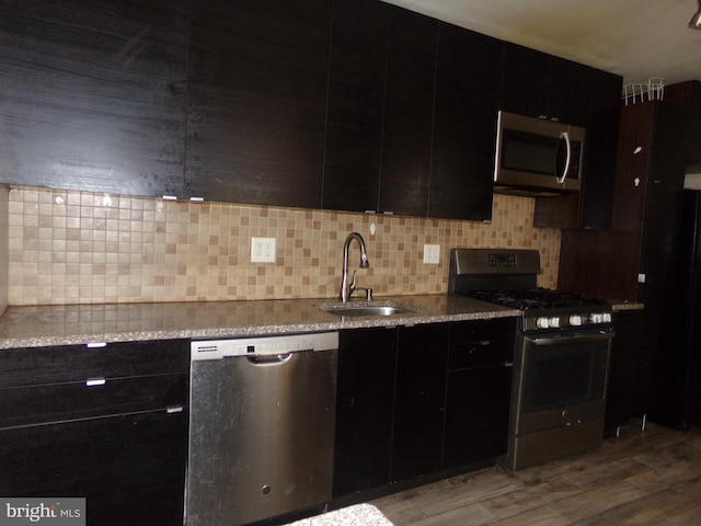 1933 N Palethorp St, Philadelphia, PA 19122 - kitchen featuring dark cabinets, appliances with stainless steel finishes, decorative backsplash, and a sink