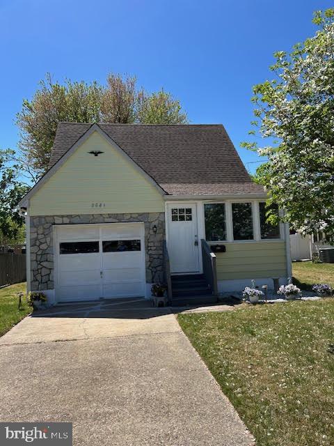 view of front of house featuring a front lawn, roof with shingles, entry steps, and concrete driveway