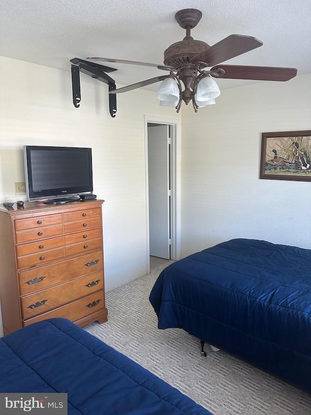 bedroom with a textured ceiling, ceiling fan, and carpet flooring
