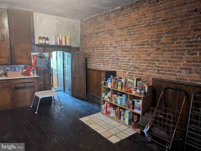 interior space featuring brick wall and dark wood-type flooring