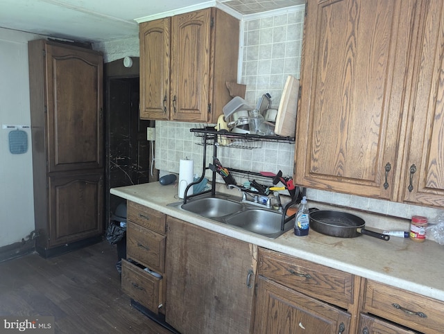 kitchen featuring light countertops, dark wood finished floors, a sink, and tasteful backsplash
