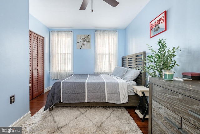 bedroom with a ceiling fan, baseboards, dark wood-style floors, and a closet