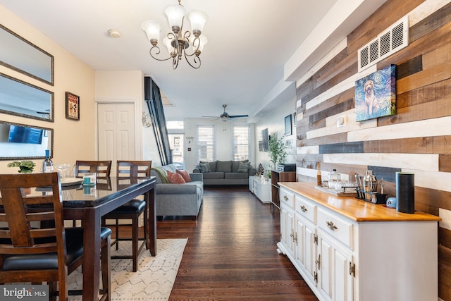 dining space with ceiling fan with notable chandelier and dark wood finished floors