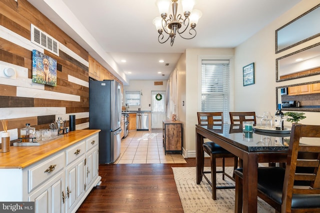 dining space featuring visible vents, wood walls, recessed lighting, a chandelier, and light wood finished floors
