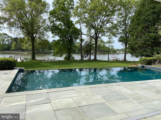 outdoor pool with a water view and a yard