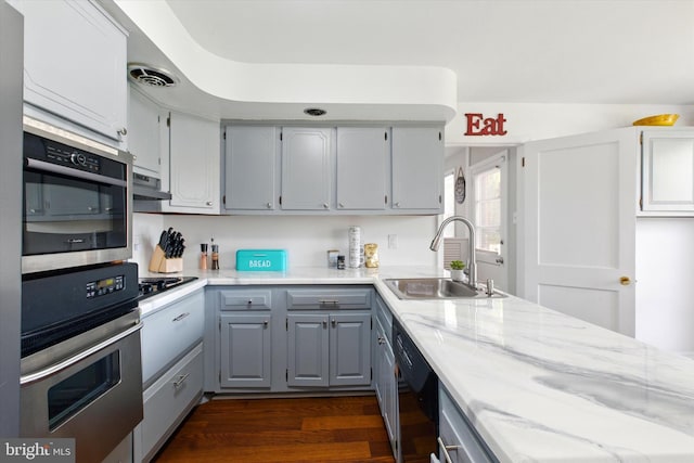 kitchen with a sink, black appliances, visible vents, ventilation hood, and gray cabinetry