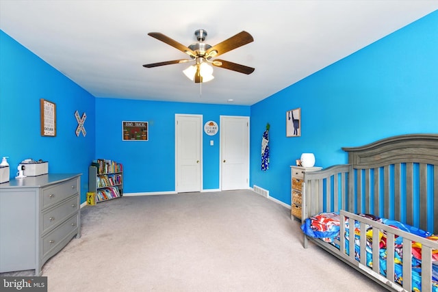 carpeted bedroom featuring a ceiling fan, visible vents, and baseboards