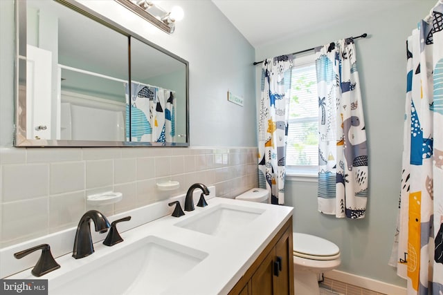 bathroom with double vanity, toilet, baseboards, and a sink