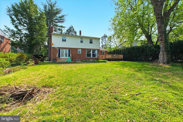 back of property with a wooden deck, brick siding, a yard, a chimney, and french doors
