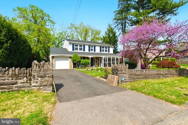 colonial inspired home with driveway, a shingled roof, covered porch, an attached garage, and a front lawn