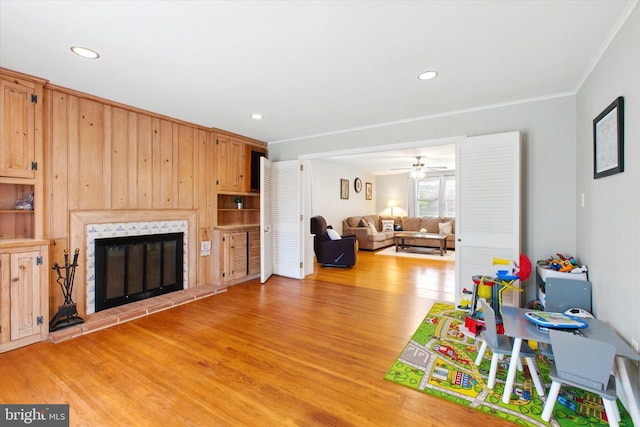 playroom featuring ornamental molding, light wood finished floors, recessed lighting, and a glass covered fireplace