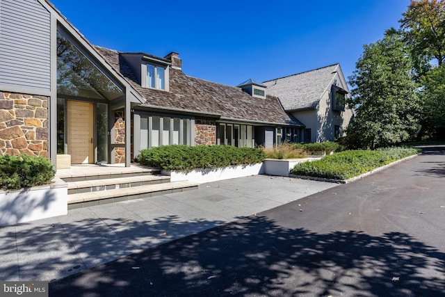 view of front of property featuring a chimney and stone siding