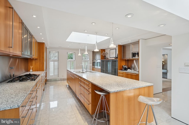 kitchen with a skylight, recessed lighting, stainless steel appliances, and brown cabinets