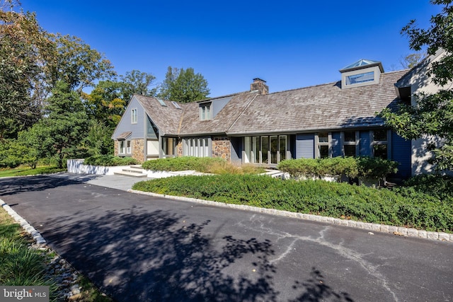 view of front of home featuring stone siding and a chimney