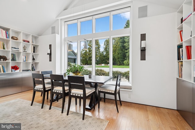 dining space with high vaulted ceiling and light wood-style flooring