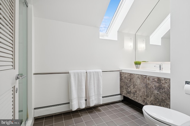 bathroom with a skylight, a shower with shower door, tile patterned floors, vanity, and toilet