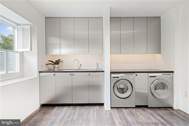 washroom with a sink, cabinet space, light wood finished floors, and washing machine and dryer