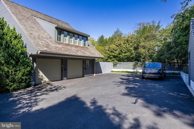 view of side of home with an attached garage, fence, and driveway