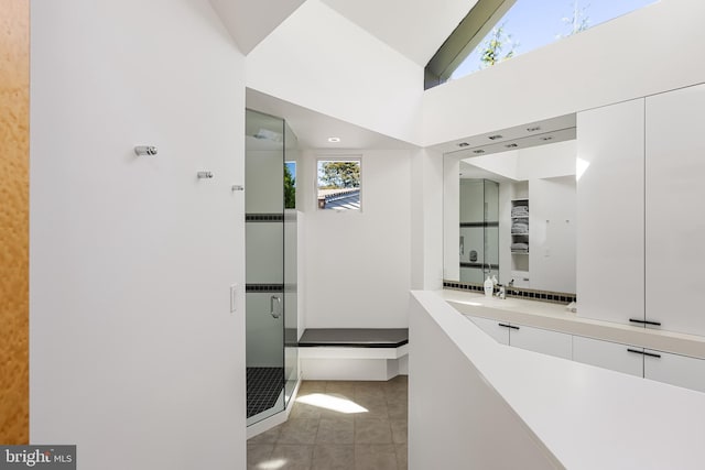 full bath with vanity, lofted ceiling, tile patterned flooring, and a shower stall