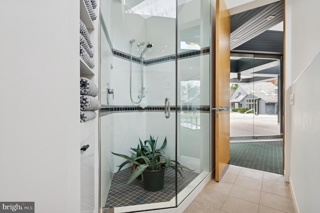 bathroom with baseboards, tile patterned flooring, and a stall shower