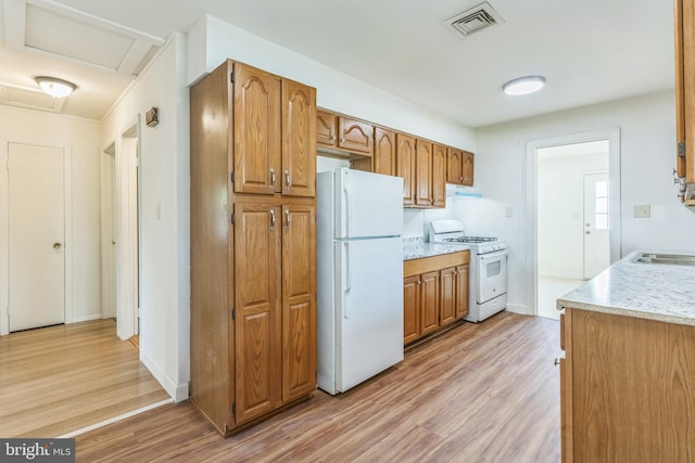 9410 Spotsylvania St, Manassas, VA 20110 - kitchen featuring ventilation hood, light wood finished floors, white appliances, brown cabinetry, and visible vents