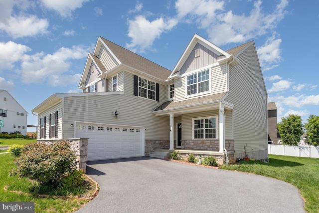 view of front of house with fence, an attached garage, stone siding, aphalt driveway, and board and batten siding