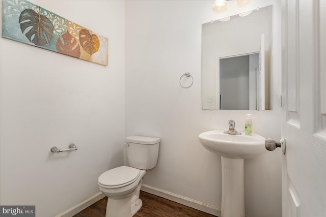 bathroom with toilet, baseboards, a sink, and wood finished floors
