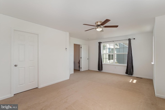 carpeted empty room featuring ceiling fan, visible vents, and baseboards